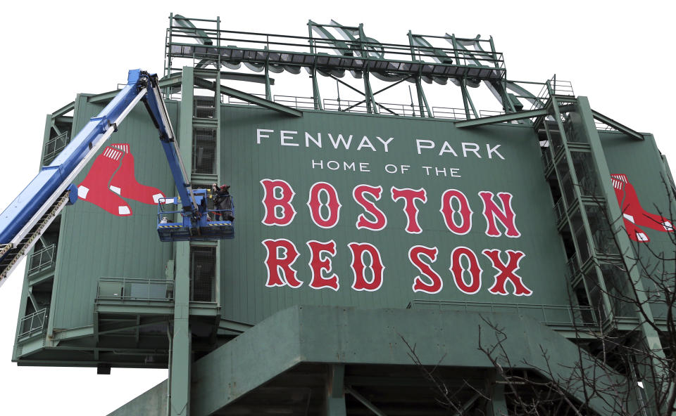 A worker in a bucket lift takes a photo after replacing the Boston Red Sox emblem on the back of the jumbo screen at Fenway Park, Thursday, Oct. 4, 2018, in Boston. The Red Sox are preparing for Game 1 of the ALDS against the New York Yankees on Friday. (AP Photo/Elise Amendola)