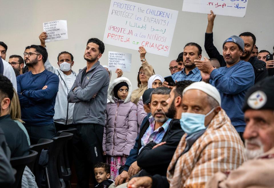 Community members hold signs protesting some educational material inside the Dearborn Schools Administrative Service Center during a Dearborn Board of Education meeting on Monday, Oct. 10, 2022.