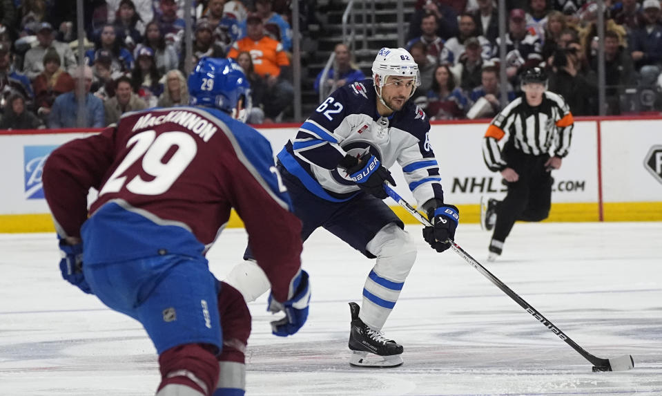 Winnipeg Jets right wing Nino Niederreiter, back, looks to pass the puck as Colorado Avalanche center Nathan MacKinnon defends during the second period of Game 3 of an NHL hockey Stanley Cup first-round playoff series Friday, April 26, 2024, in Denver. (AP Photo/David Zalubowski)