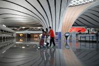 Passengers wearing face masks following the coronavirus disease (COVID-19) outbreak walk with luggages at a terminal hall of the Beijing Daxing International Airport ahead of Chinese National Day holiday, in Beijing