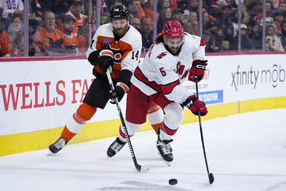 Carolina Hurricanes' Jalen Chatfield, tries to keep the puck away from Philadelphia Flyers' Sean Couturier during the second period of an NHL hockey game, Monday, Oct. 30, 2023, in Philadelphia. (AP Photo/Matt Slocum)