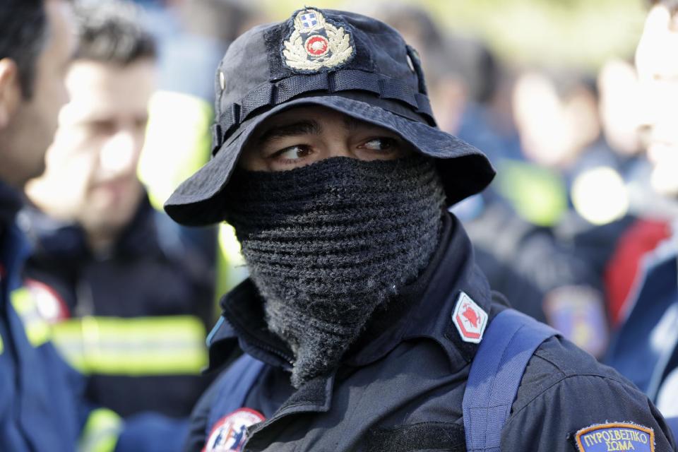 A firefighter cover his face with a scarf during a protest outside the parliament amid a contract dispute with the cash-trapped government, in Athens, Thursday, Feb. 16, 2017. The government says it is lacking the funds needed to offer thousands of firefighters long-term contracts. Greece is under pressure to make deeper spending cuts as it struggles to reach agreement with bailout lenders on the terms of future loan payouts. (AP Photo/Thanassis Stavrakis)