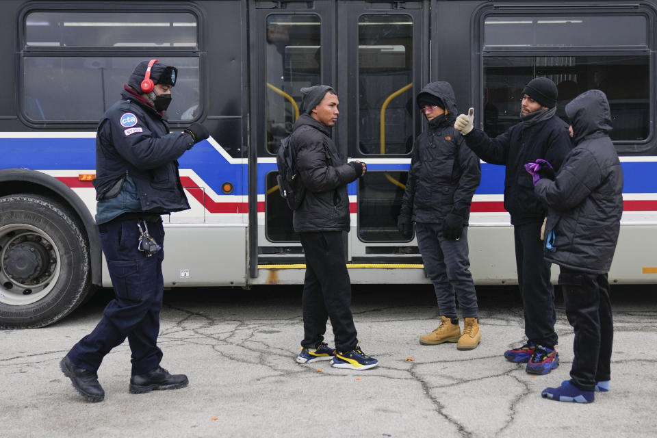 A Chicago Transit Authority worker, left, greets migrants where "warming" buses are parked in the 800 block of South Desplaines Street Thursday, Jan. 11, 2024, in Chicago. In the city of Chicago's latest attempt to provide shelter to incoming migrants, several buses were parked in the area to house people in cold winter weather. (AP Photo/Erin Hooley)