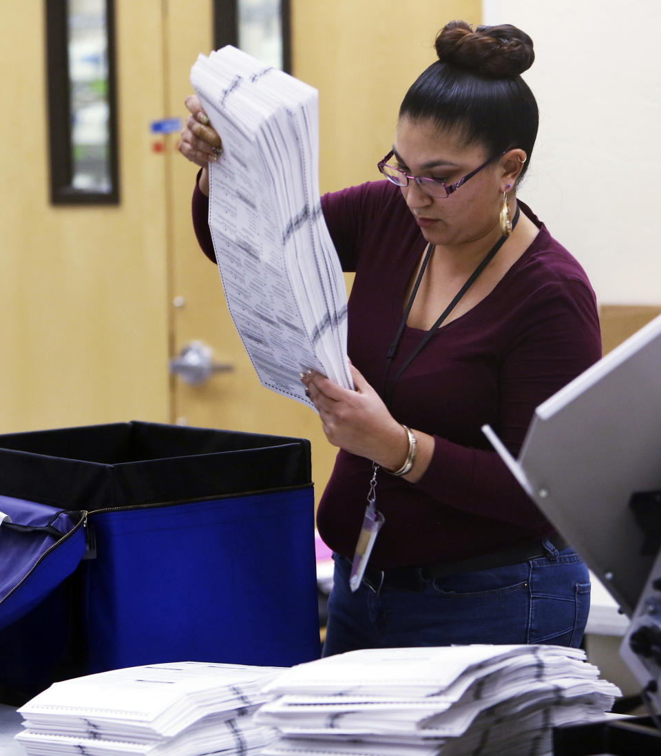 An elections worker prepares ballots before inserting them into a counting machine at Pima County Elections in Tucson, Ariz., Monday, Nov. 12, 2018. (Rick Wiley /Arizona Daily Star via AP)