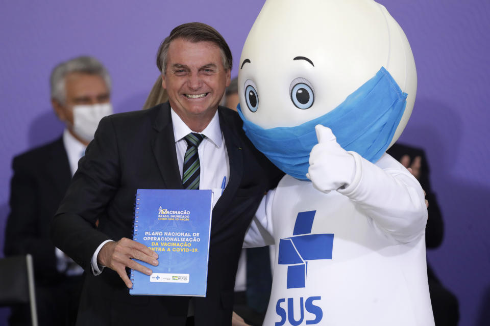 Brazilan President Jair Bolsonaro poses for photos with the mascot of the nation's vaccination campaign, named "Ze Gotinha," or Joseph Droplet, during a ceremony to present Brazil's National Vaccination Plan Against COVID-19, at Planalto presidential palace in Brasilia, Brazil, Wednesday, Dec. 16, 2020. (AP Photo/Eraldo Peres)