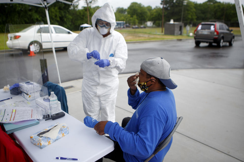 Mark Wood wipes his nose after getting a COVID-19 test administered by nurse Joyce Painter, left, at the Avondale Youth and Family Development Center on Wednesday, May 20, 2020 in Chattanooga, Tenn. Cempa Community Care was offering free walk-up and drive-thru testing for COVID-19. (C.B. Schmelter/Chattanooga Times Free Press via AP)