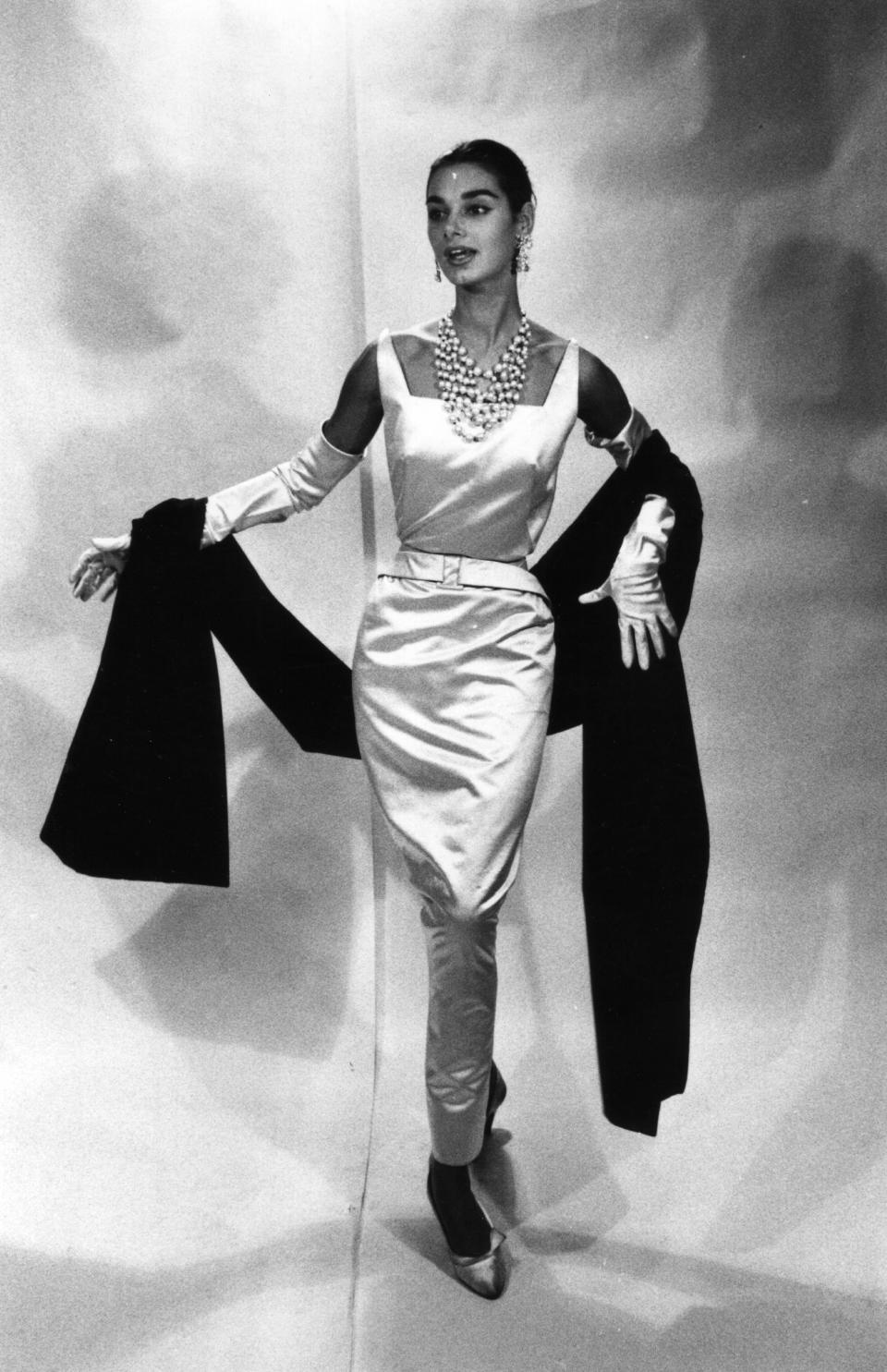 A model wears a white satin dinner dress with a stole by Givenchy.&nbsp;