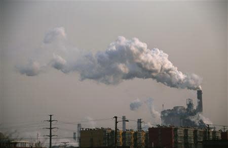 Smoke rises from a chimney of a steel plant next to residential buildings on a hazy day in Fengnan district of Tangshan, Hebei province February 18, 2014. REUTERS/Petar Kujundzic
