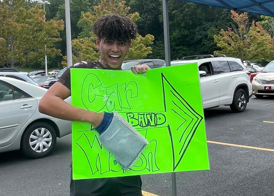 Drum major Channing Clarke helps direct the line of cars a block long at the annual car wash fundraiser for the Hardin Valley Academy Spirit of the Valley Marching Band’s Disney World trip at Food City on Middlebrook Pike Saturday, July 22, 2023.