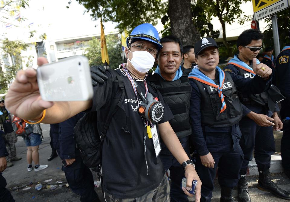 Thai riot police smile as they pose with anti-government protesters after demonstrations are called off outside Government House in Bangkok December 3, 2013. Thailand's government ordered police to stand down and allow protesters into state buildings on Tuesday, removing a flashpoint for clashes and effectively bringing an end to days of violence in Bangkok in which five people have died. REUTERS/Dylan Martinez