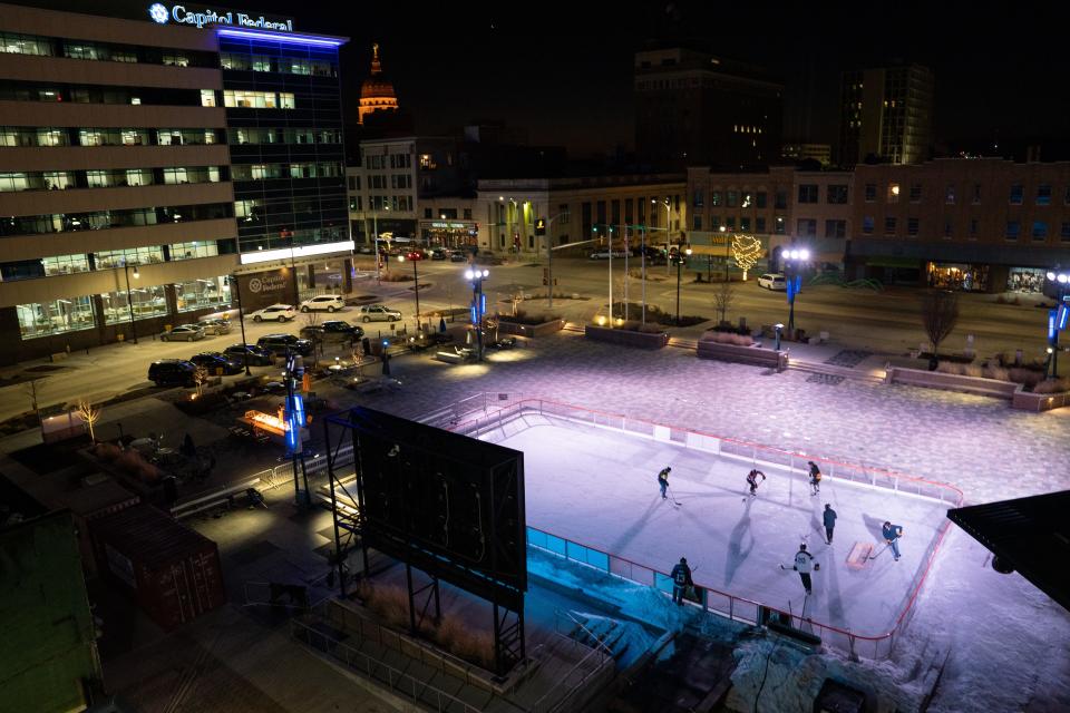 The cool blue lights surrounding Evergy Plaza makes the small group playing pond hockey on the CoreFirst ice rink stand out from the rest of downtown Topeka.