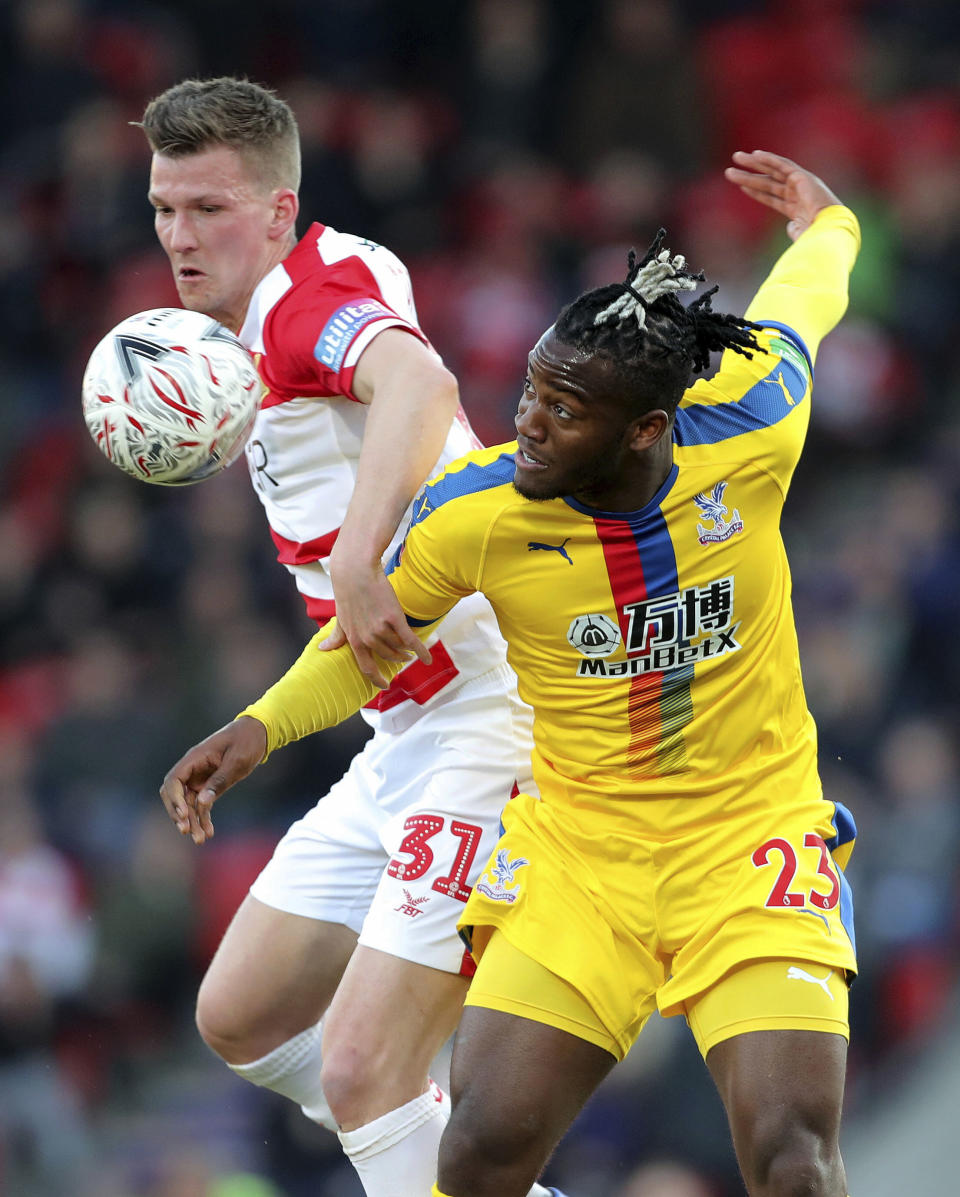 Crystal Palace's Michy Batshuayi, right, and Doncaster Rovers' Paul Downing in action during their English FA Cup fifth round soccer match at the Keepmoat Stadium in Doncaster, England, Sunday Feb. 17, 2019. (Richard Sellers/PA via AP)