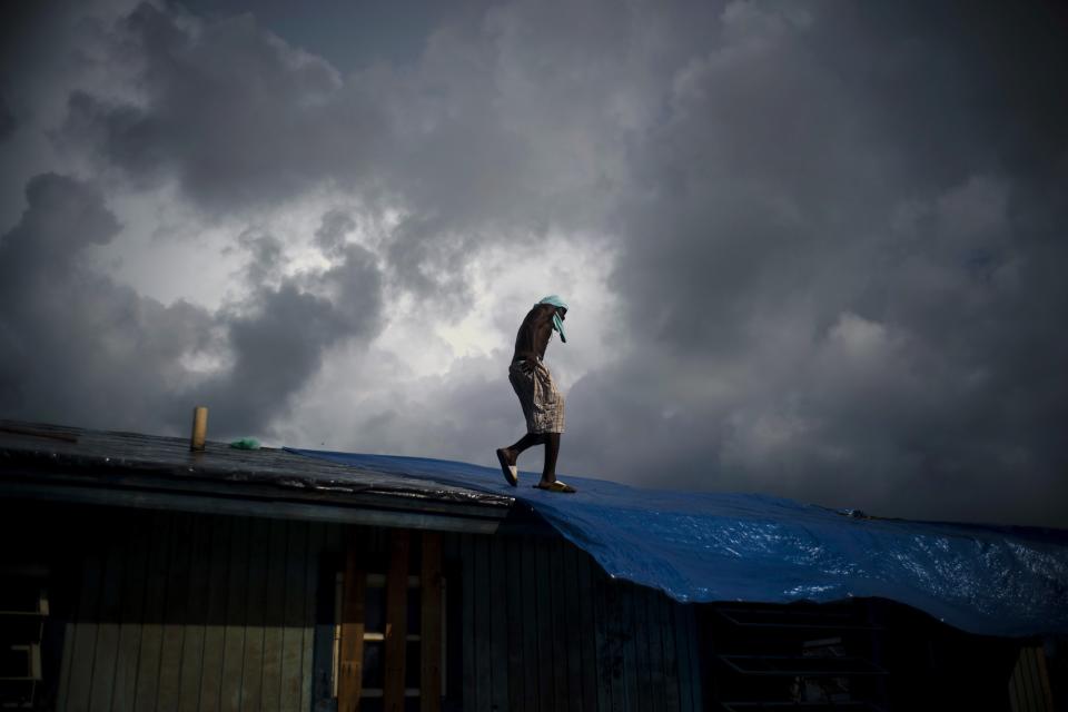 Trevon Laing walks the roof of his house to repair the damage made by Hurricane Dorian, in Gold Rock Creek, Grand Bahama, Bahamas, Thursday Sept. 12, 2019. Trevor says "After the hurricane they had me for dead, My momma was crying." When he returned, he said he found his brother crying on the front porch."I'm like, 'Hey, I'm not dead! You guys have no faith in me. I'm a survivor,'" he said, adding with a laugh, "He was shocked and mad at the same time." (AP Photo / Ramon Espinosa)