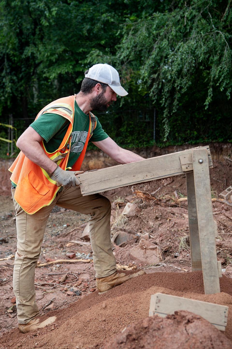 Levi King, of TRC, sifts through dirt at the site of an old cemetery in West Asheville June 22, 2023.