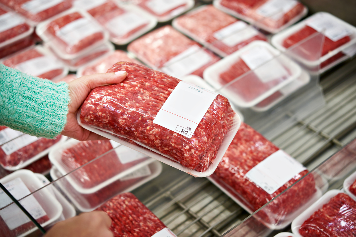 Woman picking up meat in a grocery store