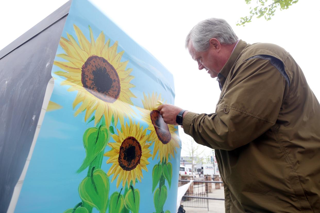Frank Westphal, an installer with Truechoice Graphics, installs one of eight vinyl-artwork wraps on a traffic control unit on May 5.