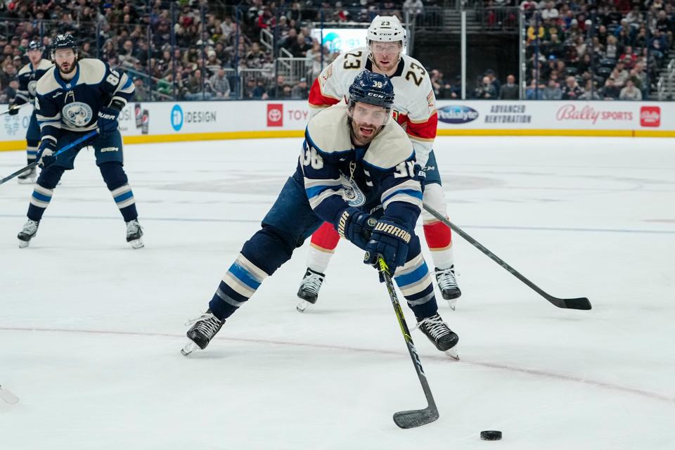 Columbus Blue Jackets center Boone Jenner (38) reaches for a puck in front of Florida Panthers center Carter Verhaeghe (23) during the first period of the NHL hockey game at Nationwide Arena on April 1, 2023.