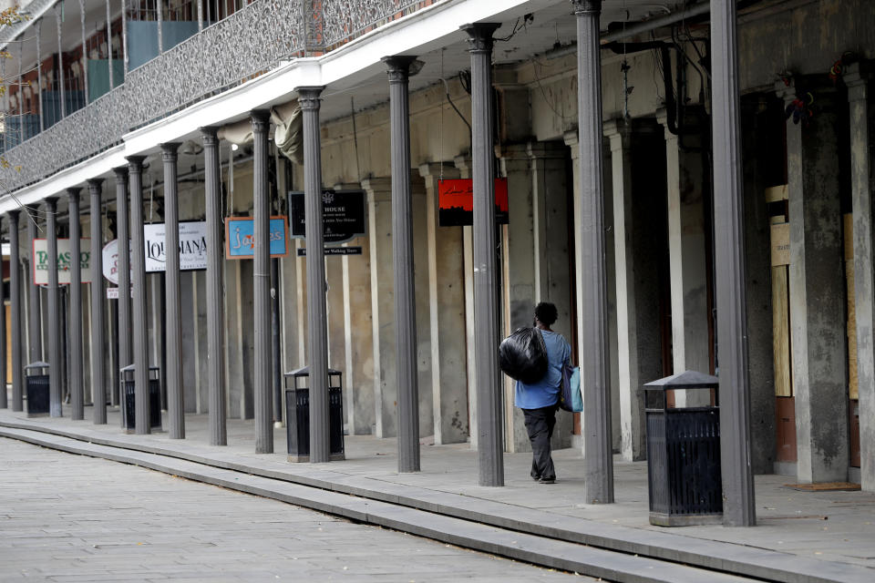 A man walks with some possessions alongside Jackson Square in the French Quarter of New Orleans, normally bustling with tourists, but now nearly deserted due to the new coronavirus pandemic, Friday, March 27, 2020. While rich in history and culture, New Orleans is economically poor, and the people here are not necessarily well-positioned to weather this latest storm. (AP Photo/Gerald Herbert)