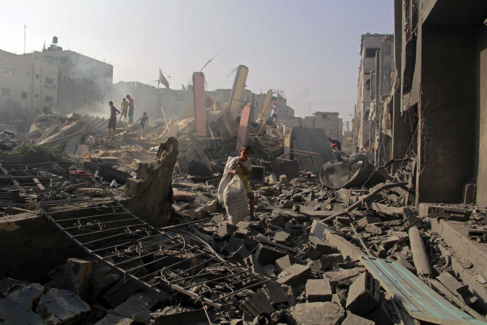 FILE - In this Aug. 2, 2014 file photo, Palestinians search through rubble of homes destroyed in Israeli strikes in Rafah, southern Gaza Strip. The Israeli military said on Wednesday Aug. 15, 2018, its investigation focused on an Aug. 1, 2014, battle in the southern Gaza town of Rafah, one of the bloodiest incidents of the 2014 war in the Gaza Strip, has found no criminal wrongdoing by Israeli forces, although human rights advocates accused the military of a whitewash. (AP Photo/Hatem Ali, FILE)