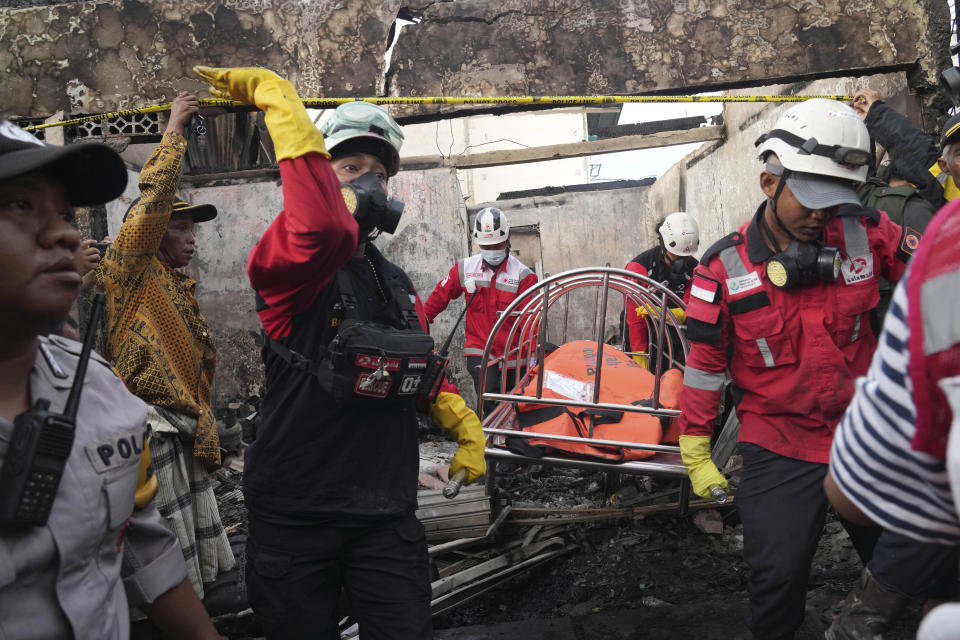 Rescuers recover the body of a victim from a neighborhood affected by a fuel depot fire in Jakarta, Indonesia, Saturday, March 4, 2023. A large fire broke out at the fuel storage depot in Indonesia's capital Friday, killing multiple people, injuring dozens of others and forcing the evacuation of thousands of nearby residents after spreading to their neighborhood, officials said. (AP Photo/Tatan Syuflana)