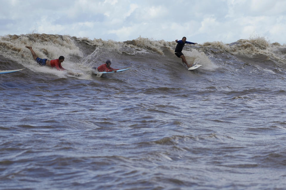 Brazilian surfer Marcelo Bibita, right, rides the tidal bore wave known as "Pororoca," during the Amazon Surf Festival held in the Canal do Perigoso, or "Dangerous Channel," at the mouth of the Amazon River near Chaves, Marajo Island archipelago, Para state, Brazil, Monday, June 5, 2023. The Pororoca, a word from an Amazonian Indigenous dialect that means "destroyer" or "great blast," happens twice a day when the incoming ocean tide reverses the river flow for a time. (AP Photo/Eraldo Peres)