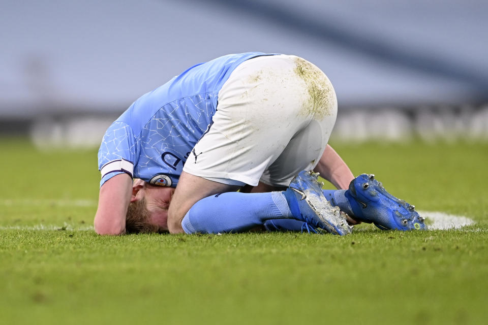 Manchester City's Kevin De Bruyne grimaces while holding his ankle during the English Premier League soccer match between Manchester City and Manchester United at the Etihad Stadium in Manchester, England, Sunday, March 7, 2021. (Laurence Griffiths/Pool via AP)