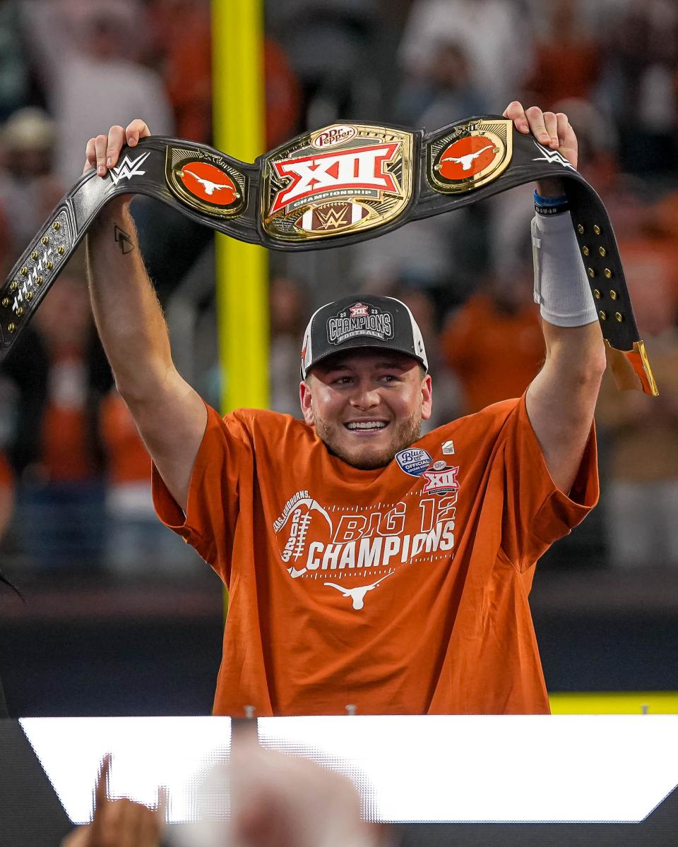 Texas quarterback Quinn Ewers holds the Big 12 championship belt that's awarded to the Big 12 Championship Game's MVP. He passed for a record 452 yards and four touchdowns in the Longhorns' 49-21 win over Oklahoma State.