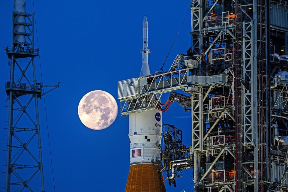 A full Moon is in view from Launch Complex 39B at NASA’s Kennedy Space Center in Florida on June 14, 2022. The Artemis I Space Launch System (SLS) and Orion spacecraft, atop the mobile launcher, are being prepared for a wet dress rehearsal to practice timelines and procedures for launch. The first in an increasingly complex series of missions, Artemis I will test SLS and Orion as an integrated system prior to crewed flights to the Moon. Through Artemis, NASA will land the first woman and first person of color on the lunar surface, paving the way for a long-term lunar presence and using the Moon as a steppingstone on the way to Mars.