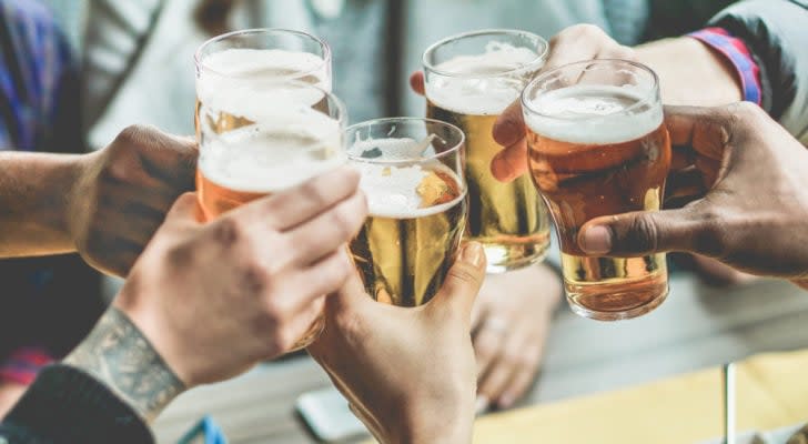 photo of peoples' hands clinking glasses of beer together in celebration