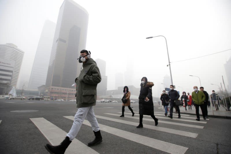 A man wearing a respiratory protection mask walks toward an office building during the smog after a red alert was issued for heavy air pollution in Beijing's central business district, China, December 21, 2016. REUTERS/Jason Lee