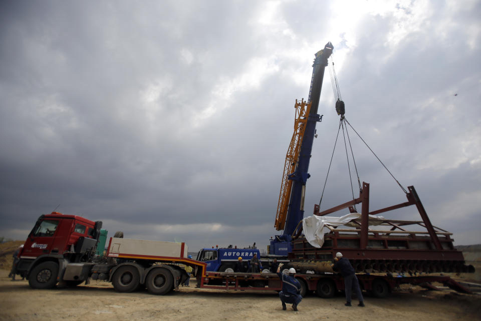 A crane lifts a complete skeleton of a mammoth, named Vika, secured in a specially made structure, at an open pit coal mine in Kostolac, 80 kilometers (50 miles) east of Belgrade, Serbia, Friday, April 11, 2014. Vika, a complete mammoth skeleton, discovered by Serbian archaeologists in 2009 inside the Kostolac open coal pit mine, was moved from the spot where it was found to a secure location because the pit mine threatened to endanger the safety of the remains. (AP Photo/Darko Vojinovic)