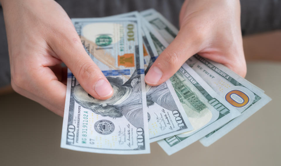 A person holding various US dollar bills