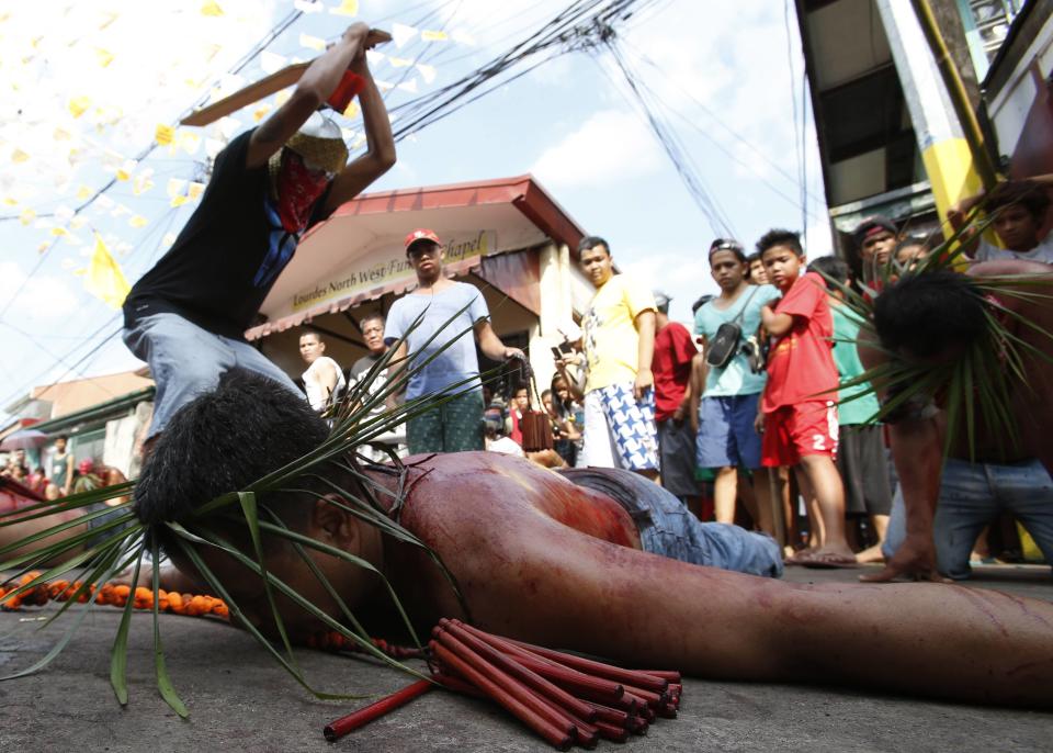 Man whips a devotee during a Maundy Thursday ritual by penitents to atone for sins in Angeles