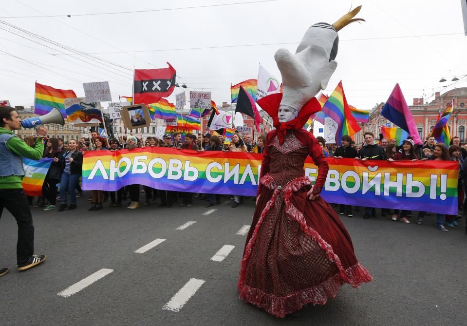 FILE - A gay rights activist wearing a mask walks ahead of a squad of gay rights activists, during a tradition May Day rally in St.Petersburg, Russia, Thursday, May 1, 2014. The poster reads : 'Love is stronger than war!' Russia’s Supreme Court on Thursday, Nov. 30, 2023, effectively outlawed LGBTQ+ activism, in the most drastic step against advocates of gay, lesbian and transgender rights in the increasingly conservative country. (AP Photo, File)