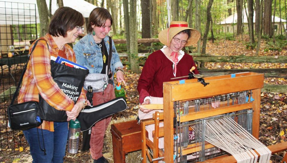 Angie Piwonka and her daughter, Molly, spend some time with Ann Jones, a weaver demonstration at Springs Folk Fest.