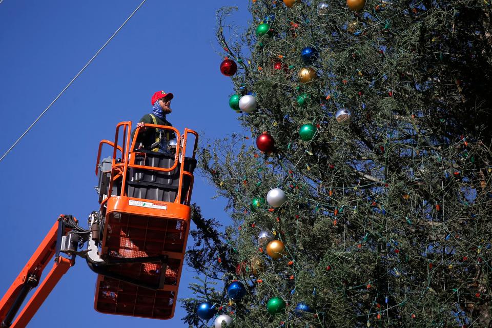 In this 2021 photo, Kaden Roney decorates a 140-foot-tall fresh-cut Christmas tree displayed as part of "The One," a Christmas event that begins with a tree-lighting ceremony in Enid.
(Photo: BRYAN TERRY/THE OKLAHOMAN)