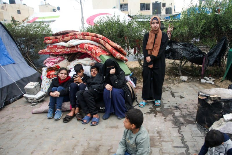 A Palestinian family sits on the pavement with children, seeking refuge from Israeli attacks on Gaza, establish makeshift tents in vacant areas to ensure their safety in Rafah. Photo by Ismael Mohamad/UPI