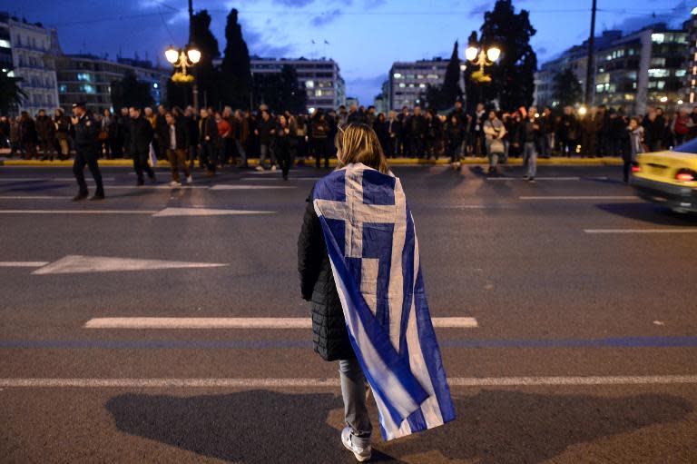 A woman wrapped in a greek flag makes her way in front of the Greek parliament in Athens on February 5, 2015 as people gather in support of the new anti-austerity government's efforts to renegotiate Greece's international loans