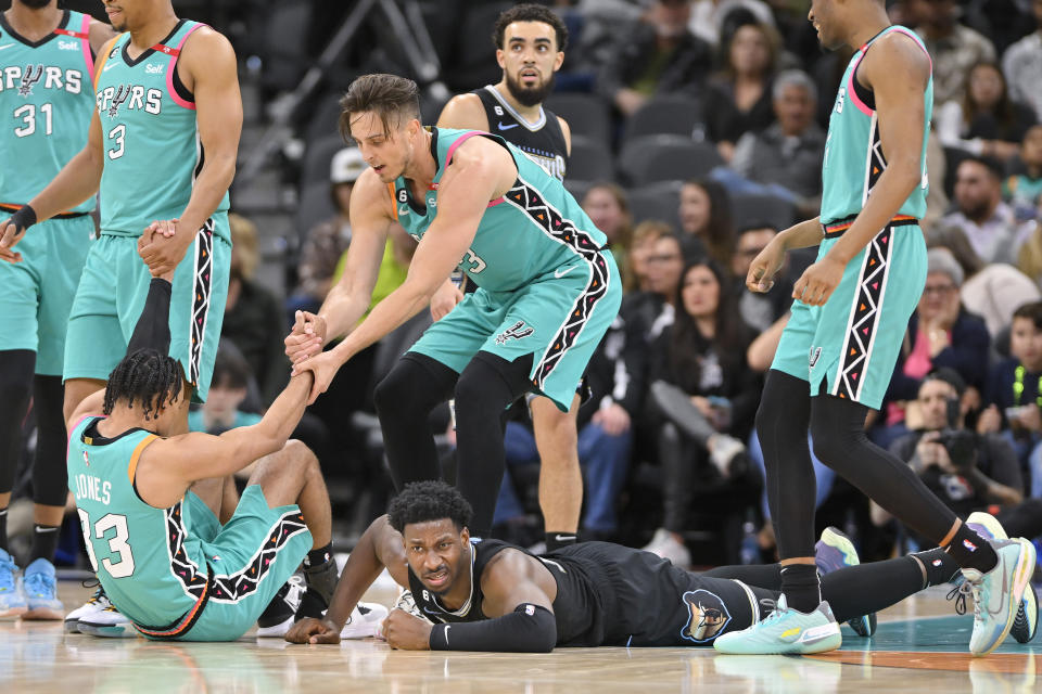 Memphis Grizzlies' Jaren Jackson Jr., bottom right, gets up after colliding with San Antonio Spurs' Tre Jones (33) during the first half of an NBA basketball game, Friday, March 17, 2023, in San Antonio. (AP Photo/Darren Abate)