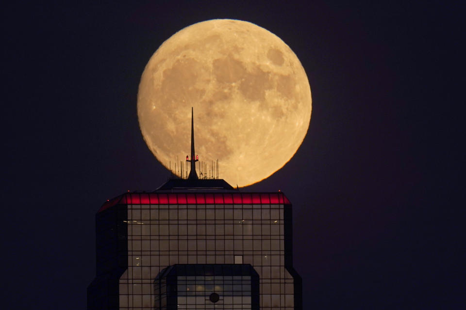 FILE - In this Wednesday, Sept. 30, 2020, file photo, a nearly full moon rises, with an office building in the foreground, in downtown Kansas City, Mo. The moon’s shadowed, frigid nooks and crannies may hold frozen water in more places and in larger quantities than previously suspected, good news for astronauts at future lunar bases who could tap into these resources for drinking and making rocket fuel, scientists reported Monday, Oct. 26, 2020. (AP Photo/Charlie Riedel, File)