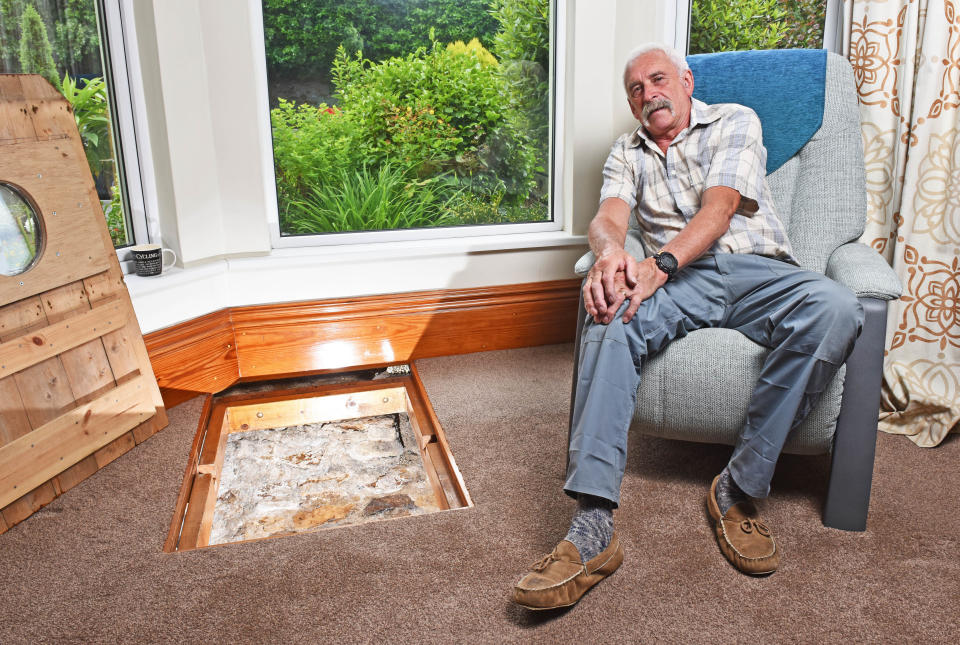 CATERS NEWS (PICTURED - Colin Steer sitting beside the well in his living room) - A grandad has spent the last decade digging out a 17ft deep medieval well in his living room after noticing a slight dip in the floor when redecorating. Colin Steer, from Plymouth, discovered the well after he noticed a dip in the floor while redecorating his living room ten years ago and has since spent the last decade digging out the 17ft well. The 70-year-old believes that the well could date back to medieval times after discovering an old sword while digging out the well and plans of the site suggests that the well could date back to the 1500s. Colin said: 