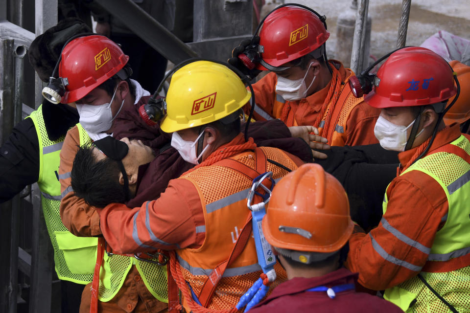 In this photo released by Xinhua News Agency, rescuers carry a miner who was trapped in a mine to an ambulance in Qixia City in east China's Shandong Province, Sunday, Jan. 24, 2021. Eleven workers trapped for two weeks by an explosion inside a Chinese gold mine were brought safely to the surface on Sunday. (Chen Hao/Xinhua via AP)