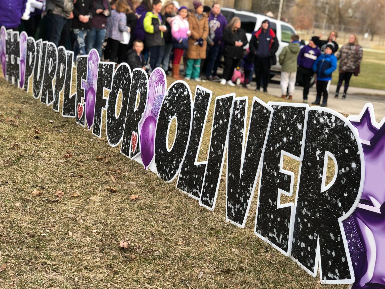 A crowd of hundreds gathered around a memorial including a #PurpleForOliver sign at a memorial for Oliver Hitchcock in Sheboygan Falls on Sunday, April 11, 2022.