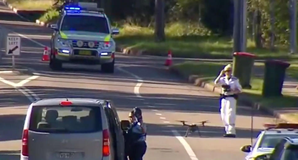 A police officer armed with a drone checks Mount Hall Road in Raymond Terrace after a 15-year-old boy died. The teen was riding a bike and was hit by a bus.