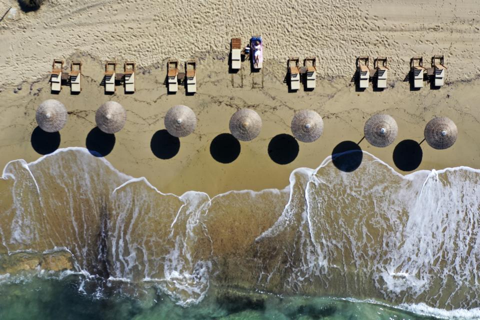 A woman enjoys the sun at Plaka beach on the Aegean island of Naxos, Greece, Friday, May 14, 2021. Greece launched its tourism season Friday amid a competitive scramble across the Mediterranean to lure vacationers emerging from lockdowns. (AP Photo/Thanassis Stavrakis)