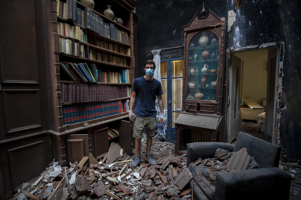 Said Al Assaad, 24, poses for a photograph inside his grandfather's destroyed villa after Tuesday's explosion in the seaport of Beirut, Lebanon, Thursday, Aug. 6, 2020. The gigantic explosion in Beirut on Tuesday tore through homes, blowing off doors and windows, toppling cupboards, and sent flying books, shelves, lamps and everything else. Within a few tragic seconds, more than a quarter of a million people of the Lebanese capital's residents were left with homes unfit to live in. Around 6,200 buildings are estimated to be damaged. (AP Photo/Hassan Ammar)