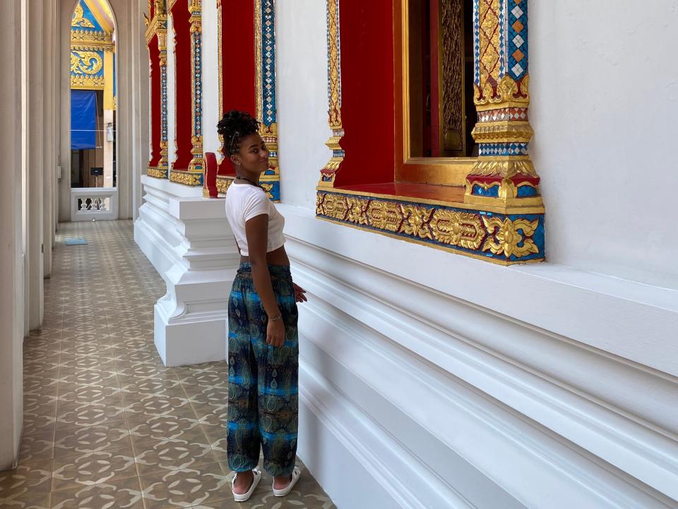 Dominique posing next to intricate architecture of temples in Bangkok Thailand