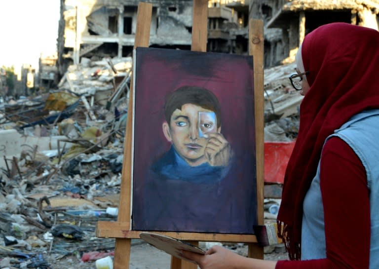 Artist Hinaya Kibabi works on a painting during a visit to the Yarmuk Palestinian refugee camp on the southern outskirts of Damascus on August 15, 2018