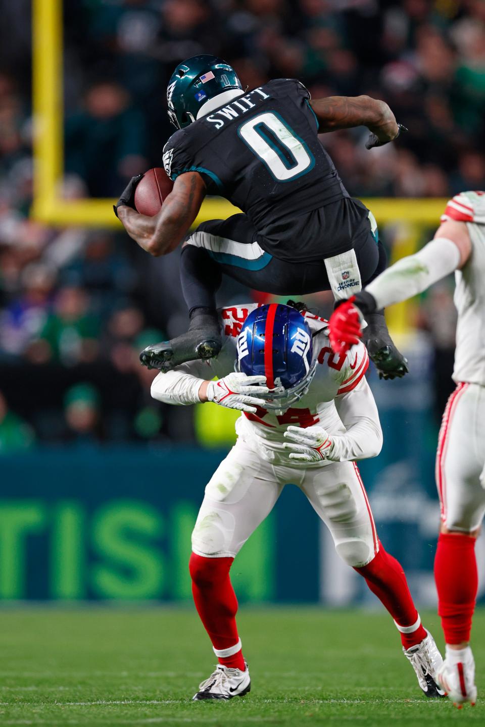 Philadelphia Eagles running back D'Andre Swift (0) hurdles over New York Giants safety Dane Belton (24) during the fourth quarter an NFL football game, Monday, Nov. 25, 2023, in Philadelphia. The Eagles defeated the Giants 33-25.