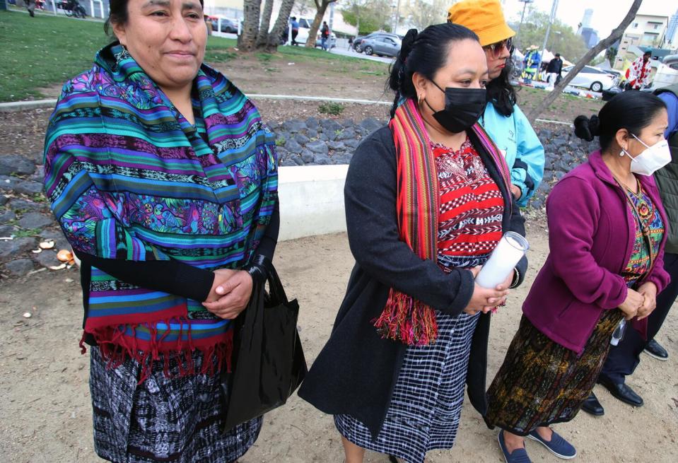 People stand next to each other with their hands folded at their waist.